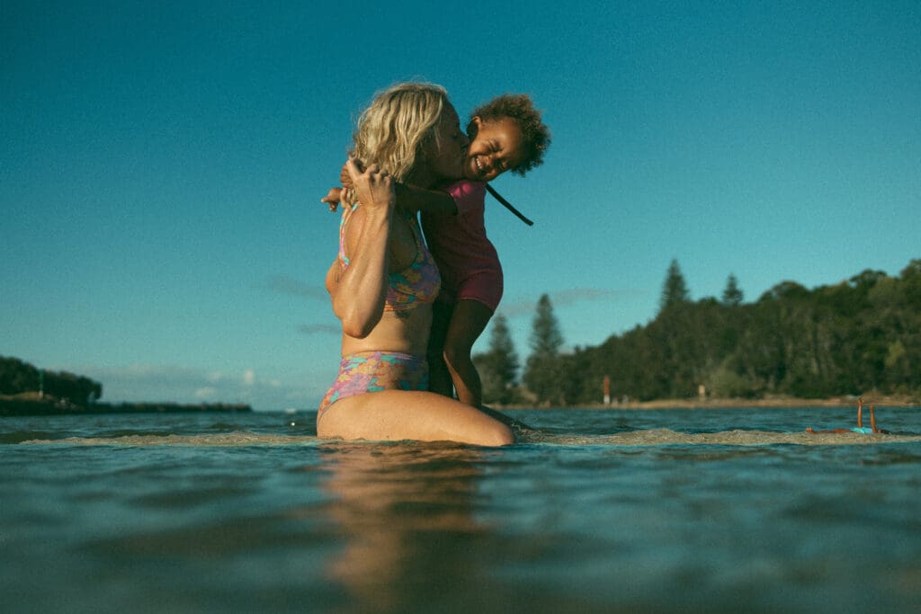 mother kissing her daughter on her surf board in Evans Head NSW