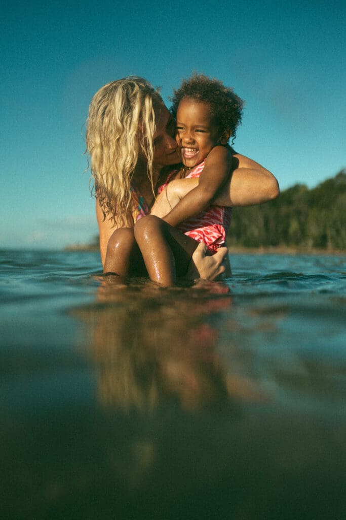 Mother cuddling her child in the water in Evans River at Evans Head NSW